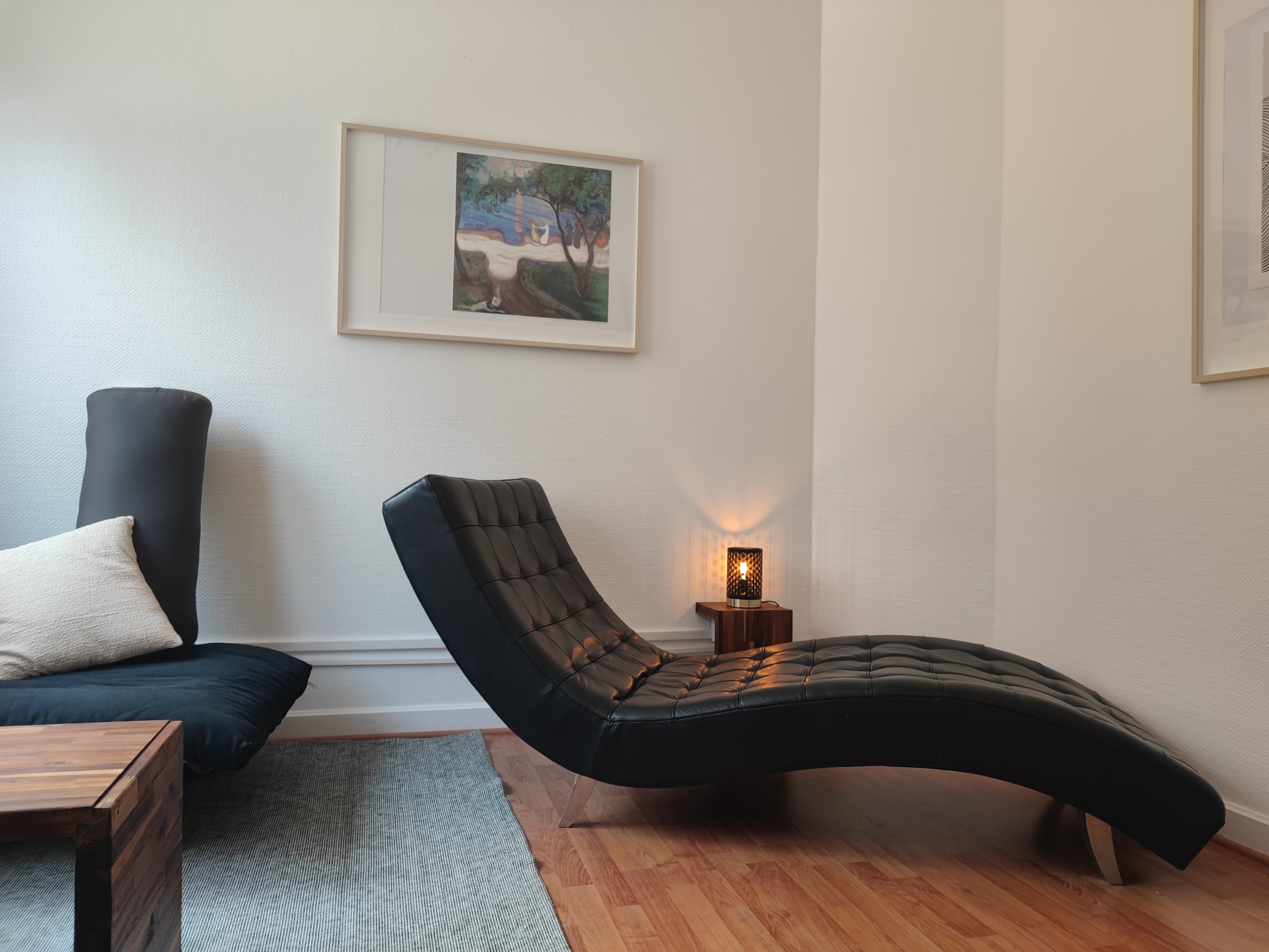 Cabinet de Cyrielle Weisgerber avec fauteuil, divan, bureau fait main, cadre sur le mur, petite lampe allumée